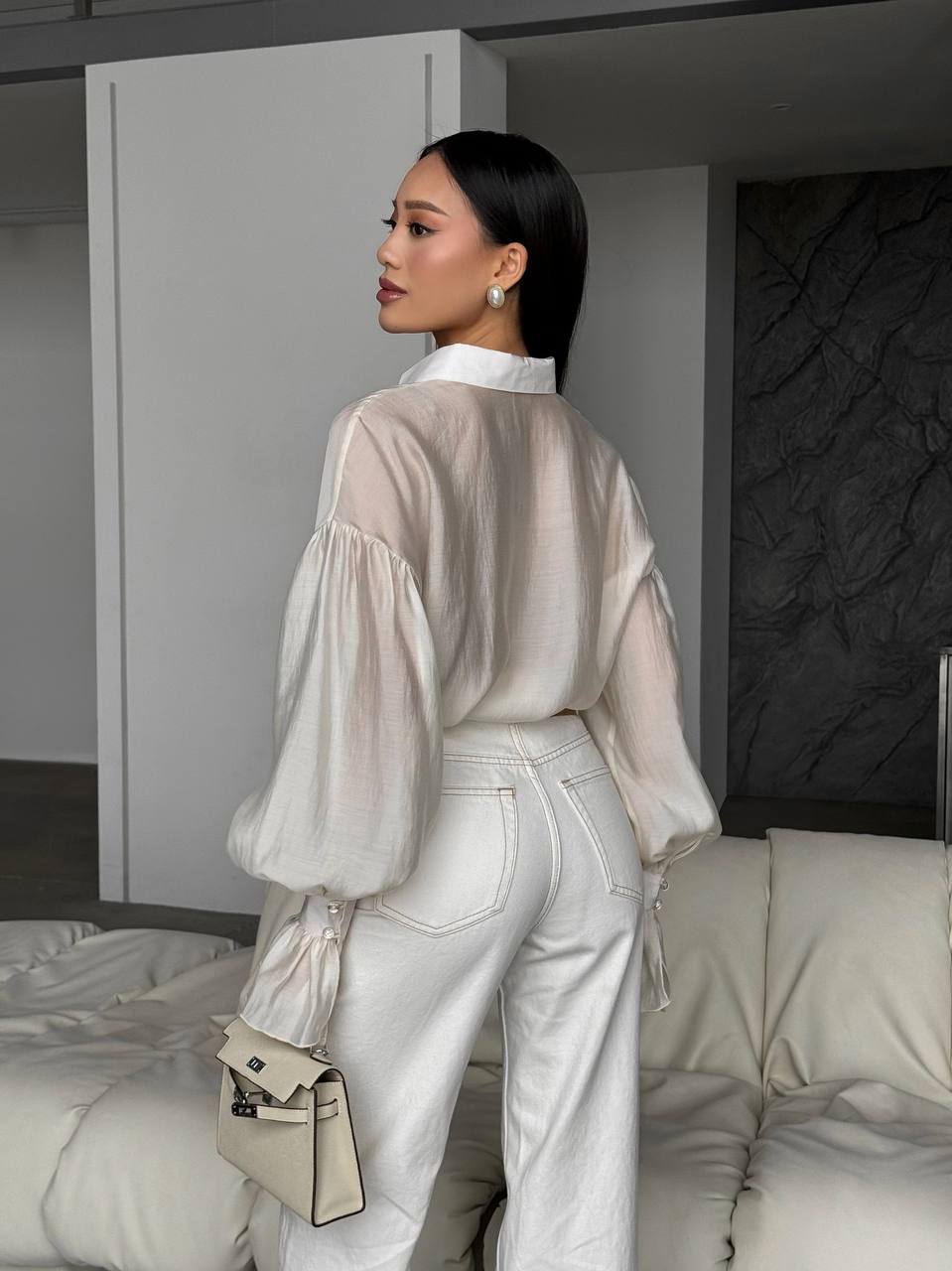 Woman in a stylish outfit with a neutral color palette in an indoor setting.