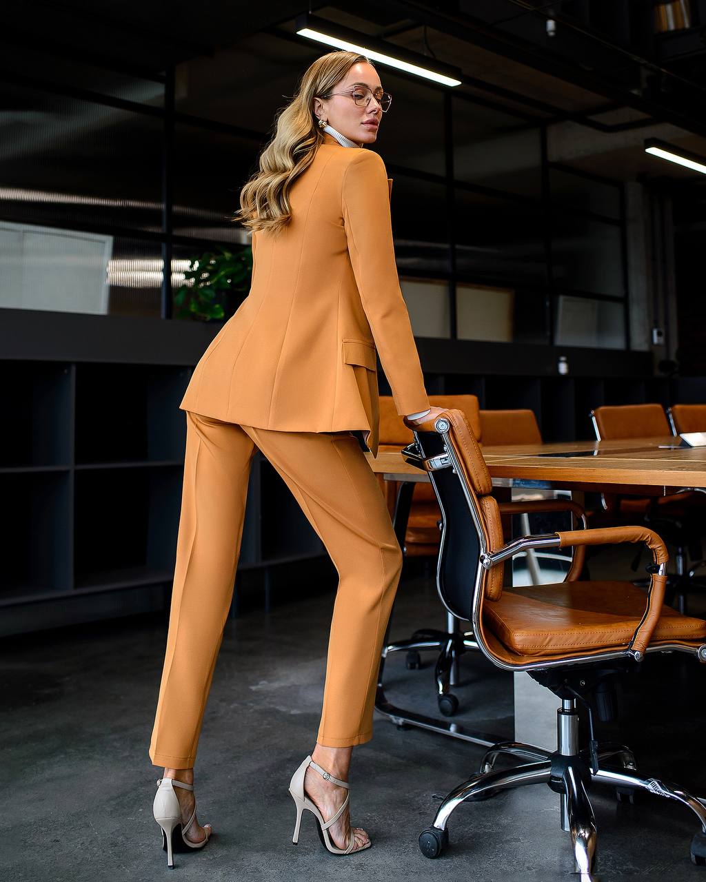 Woman in a mustard yellow suit standing in an office setting.