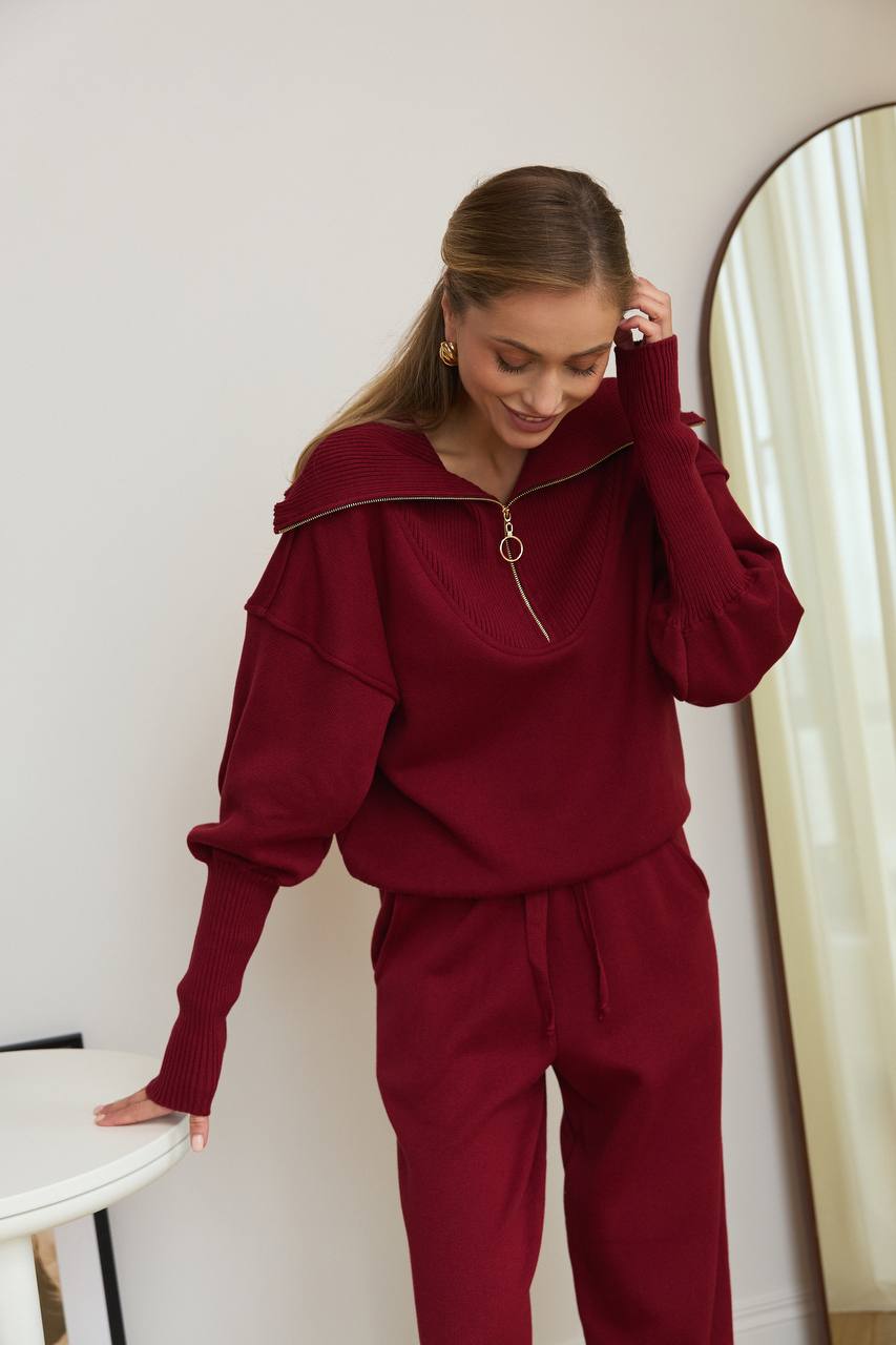 Woman wearing a burgundy outfit standing in front of a mirror.