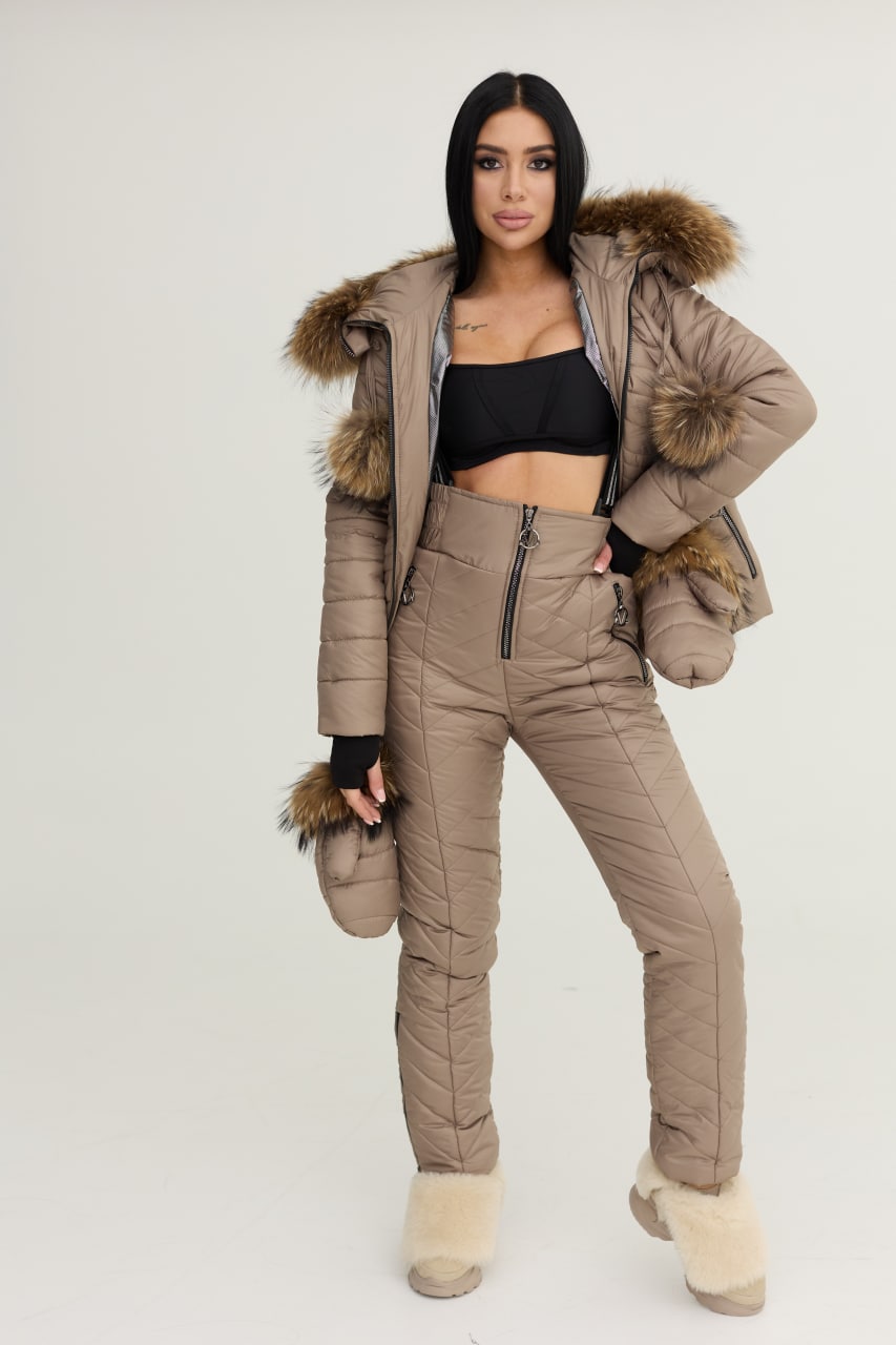 Woman wearing a beige puffer jacket and pants with fur trim on a white background