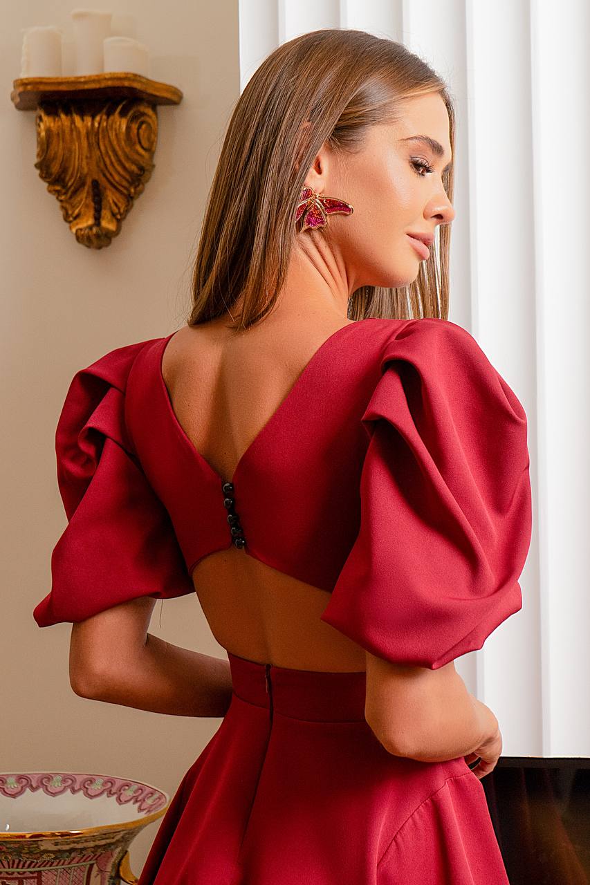 Woman wearing a red dress with puffed sleeves in an indoor setting