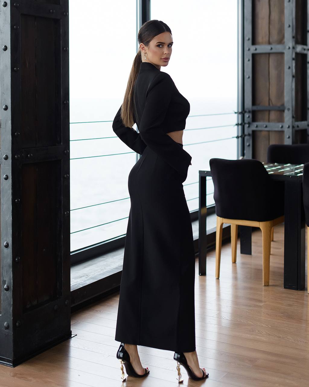Woman in a black outfit standing in a modern interior setting