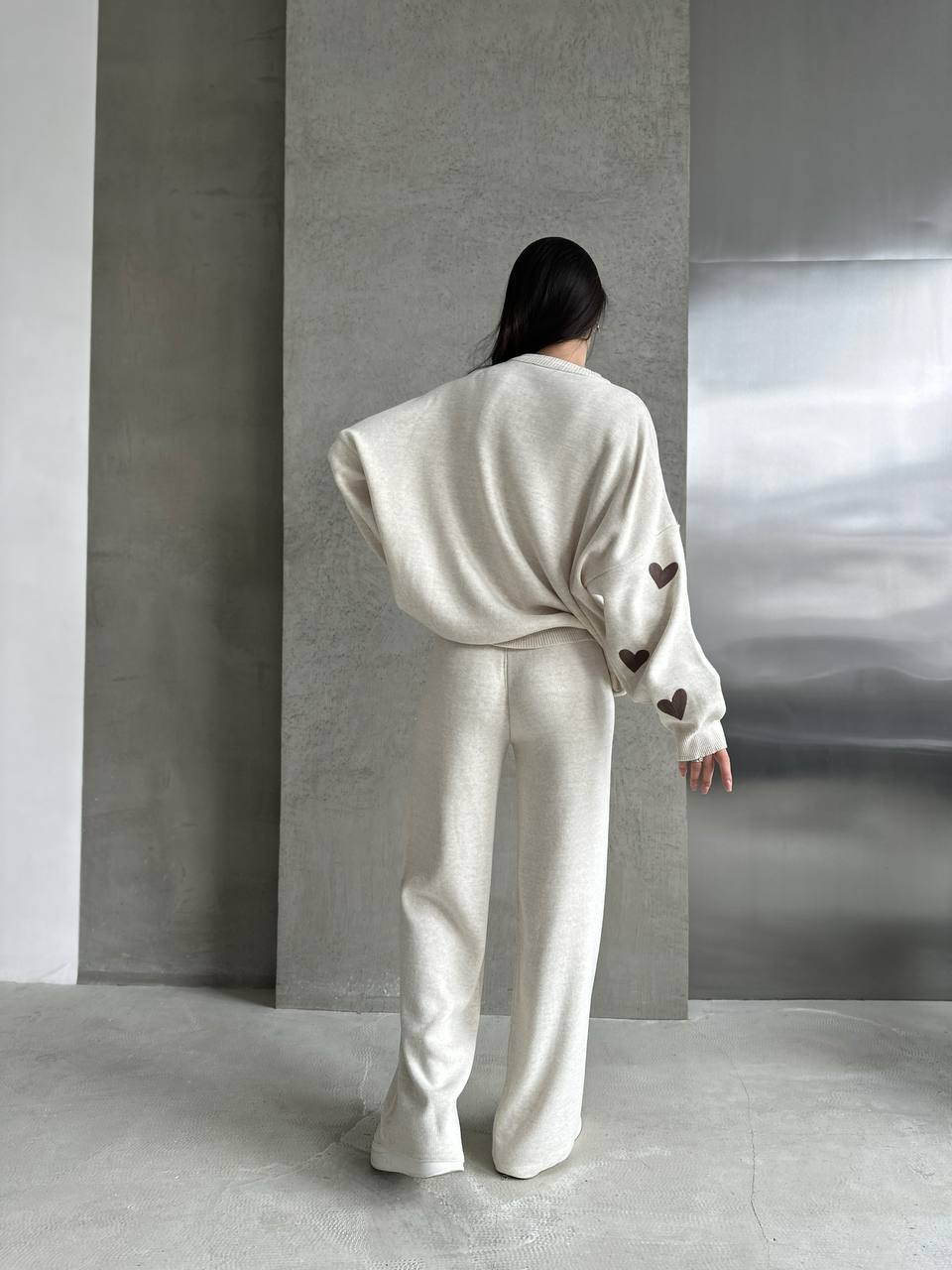 Person wearing a white outfit with heart patterns in a minimalistic setting