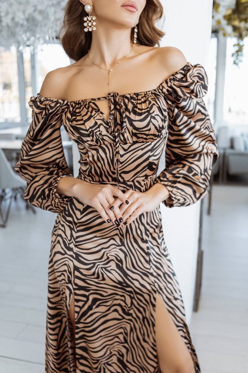Woman wearing a zebra print off-shoulder dress in an indoor setting.