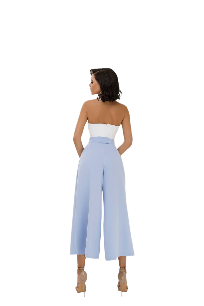 Woman wearing a strapless white top and light blue wide-leg pants on a white background