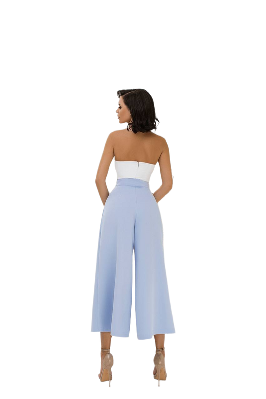 Woman wearing a strapless white top and light blue wide-leg pants on a white background