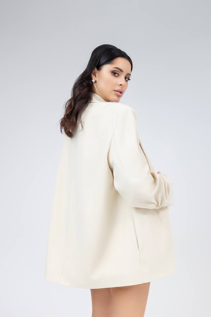 Woman wearing a cream blazer against a white background