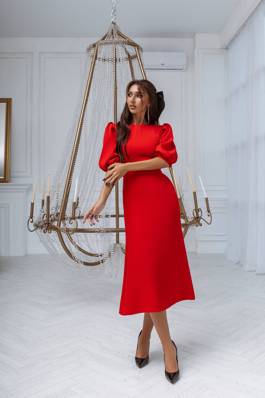 Woman in a red dress standing in a room with a decorative chandelier.
