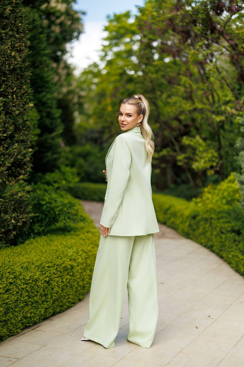 Woman in a light green suit walking through a garden
