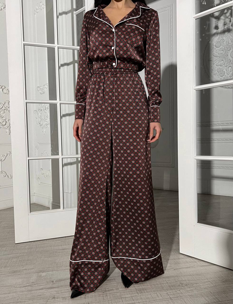 Woman wearing a patterned pajama set standing in a room with white doors.