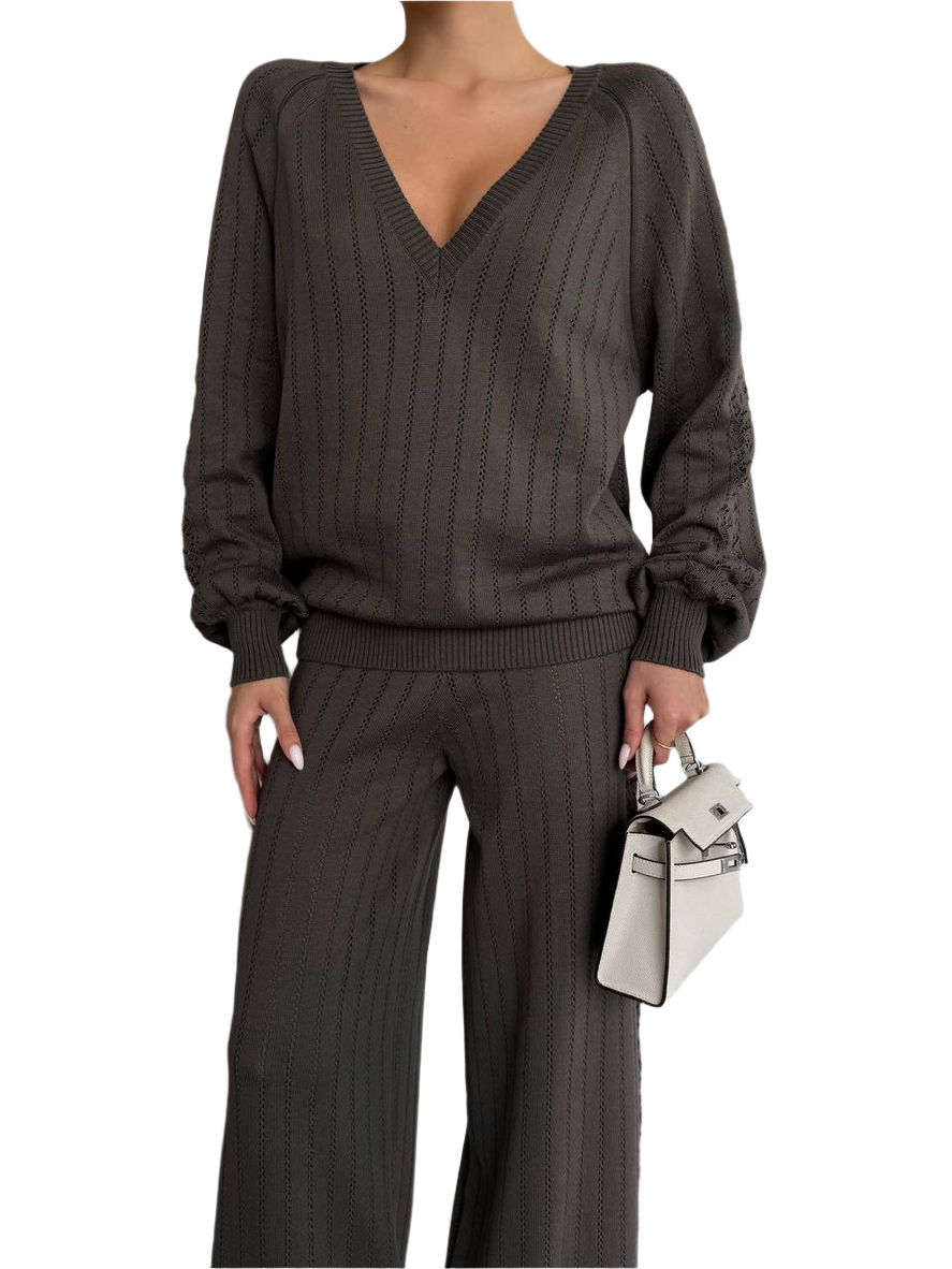 Person wearing a brown ribbed sweater and pants with a white background