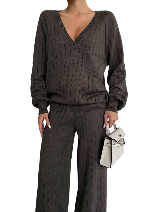 Person wearing a brown ribbed sweater and pants with a white background