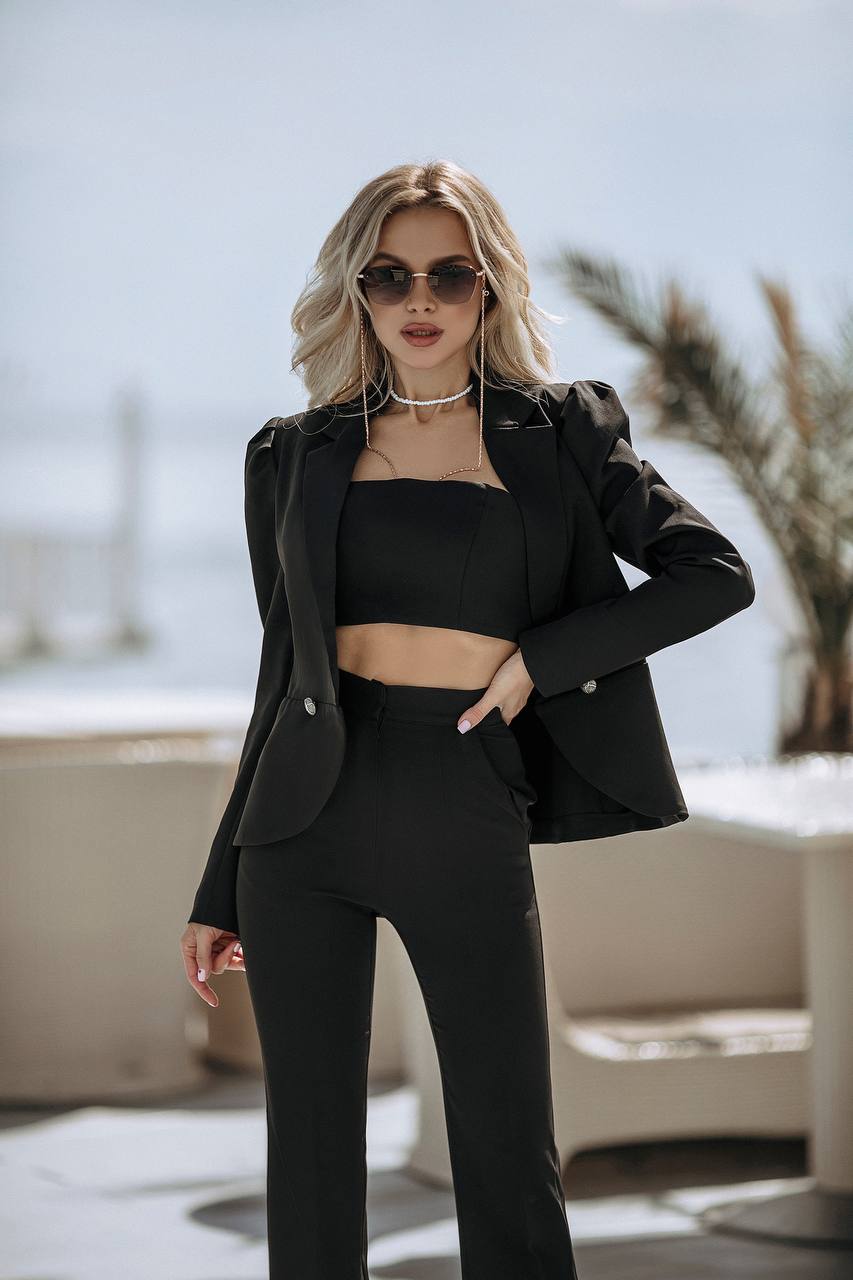 Woman in a black outfit standing in an outdoor setting with blurred background