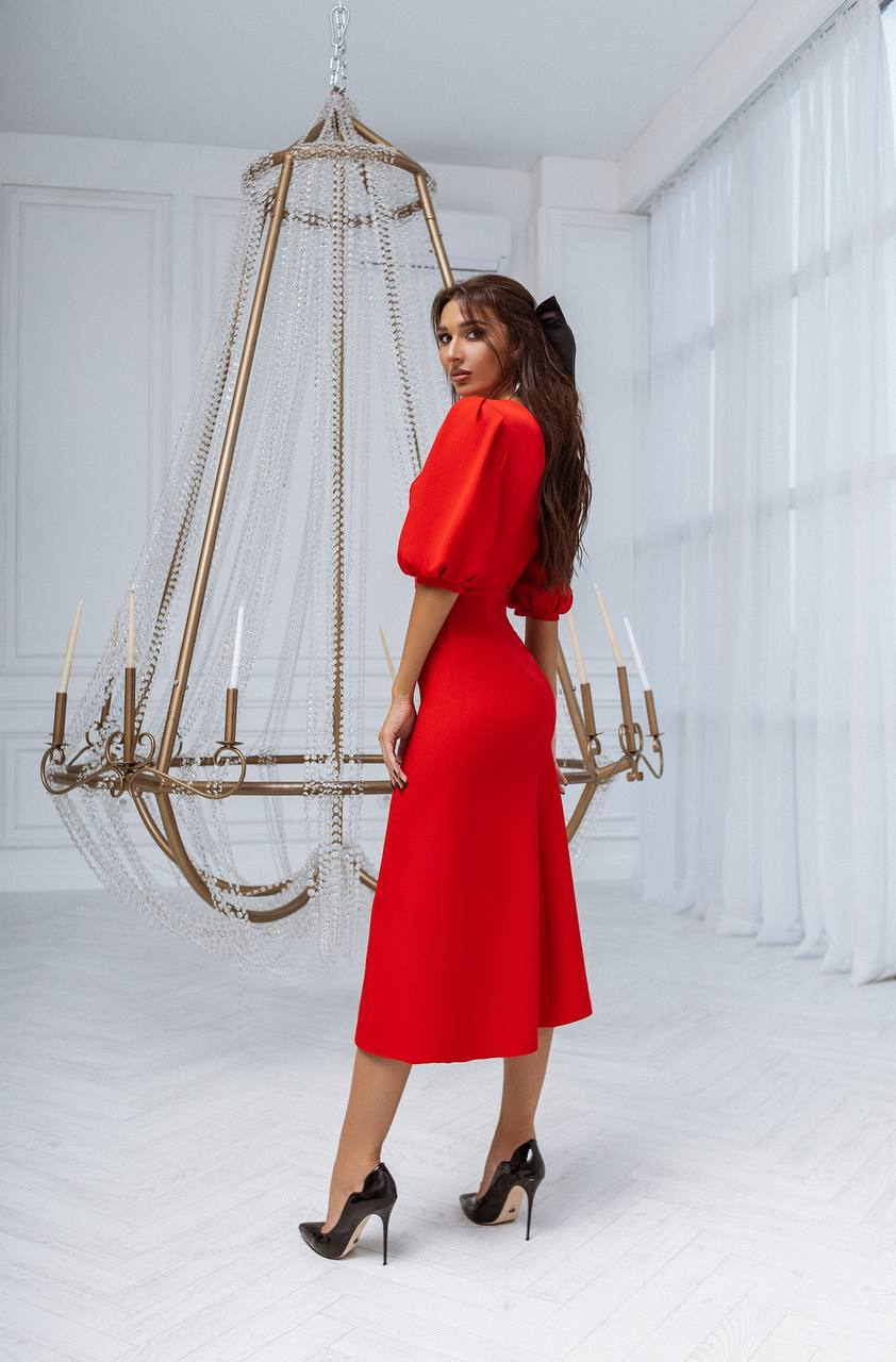 Woman in a red dress standing in a room with a large chandelier.