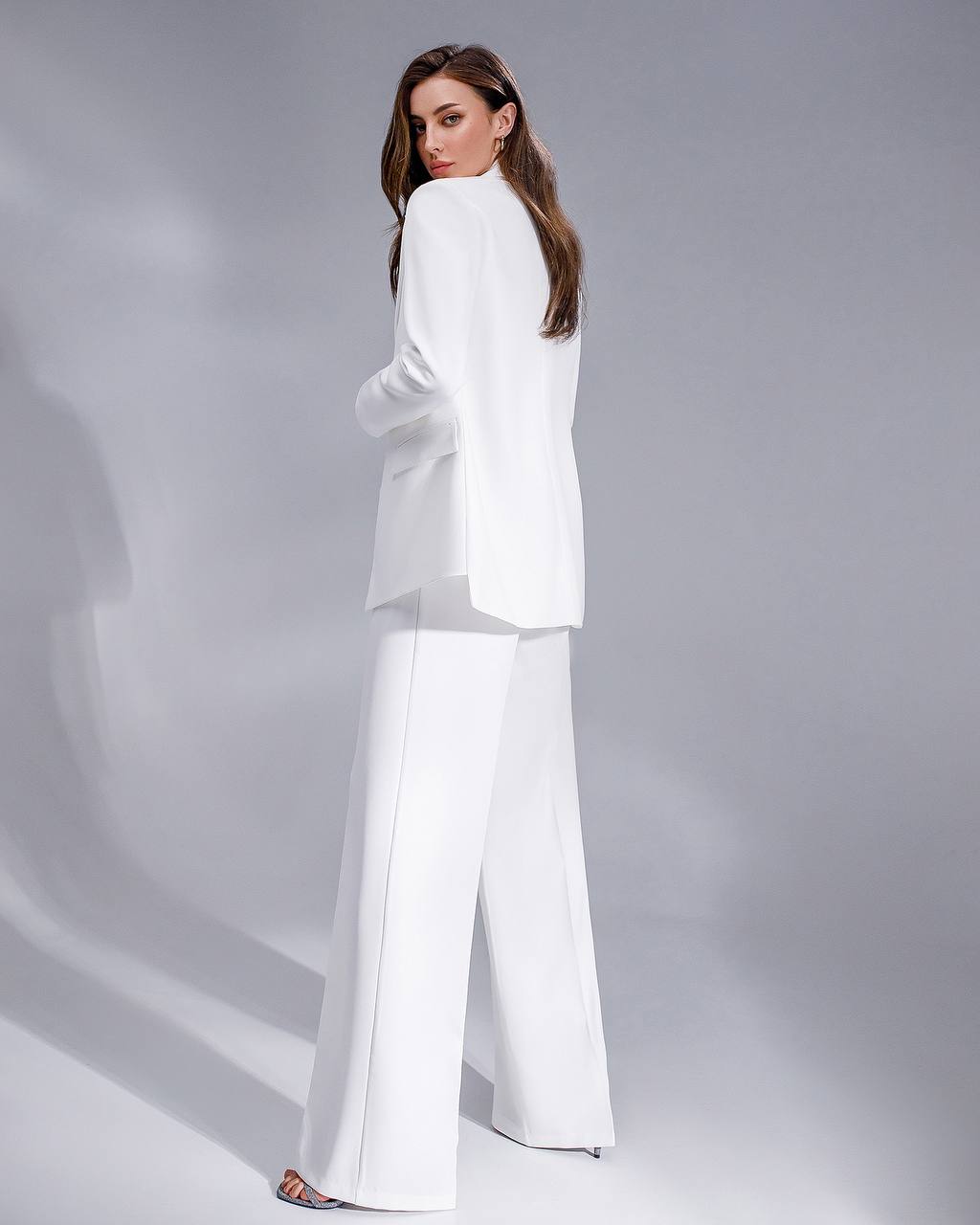 Woman wearing a white suit on a gray background