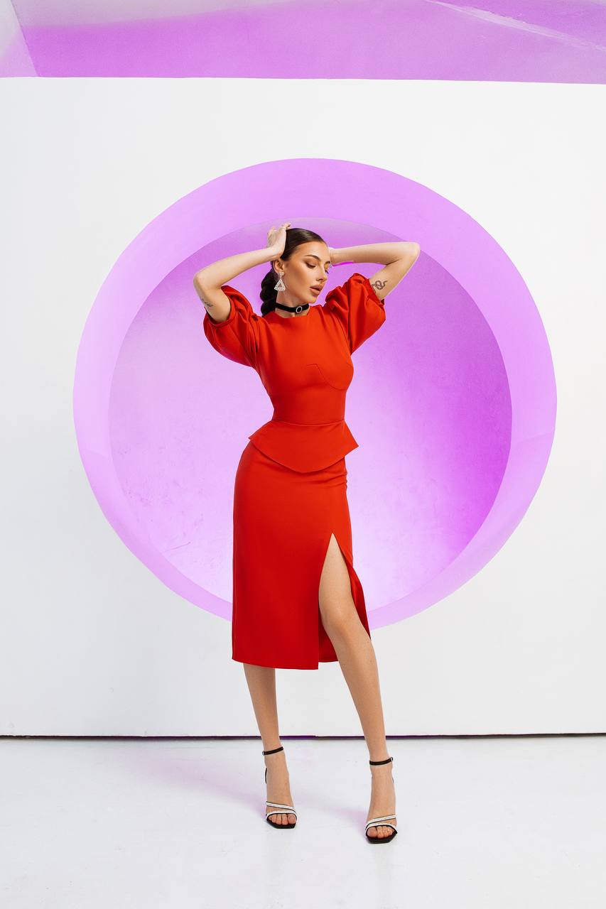 Woman in a red dress posing against a white background with a purple circle