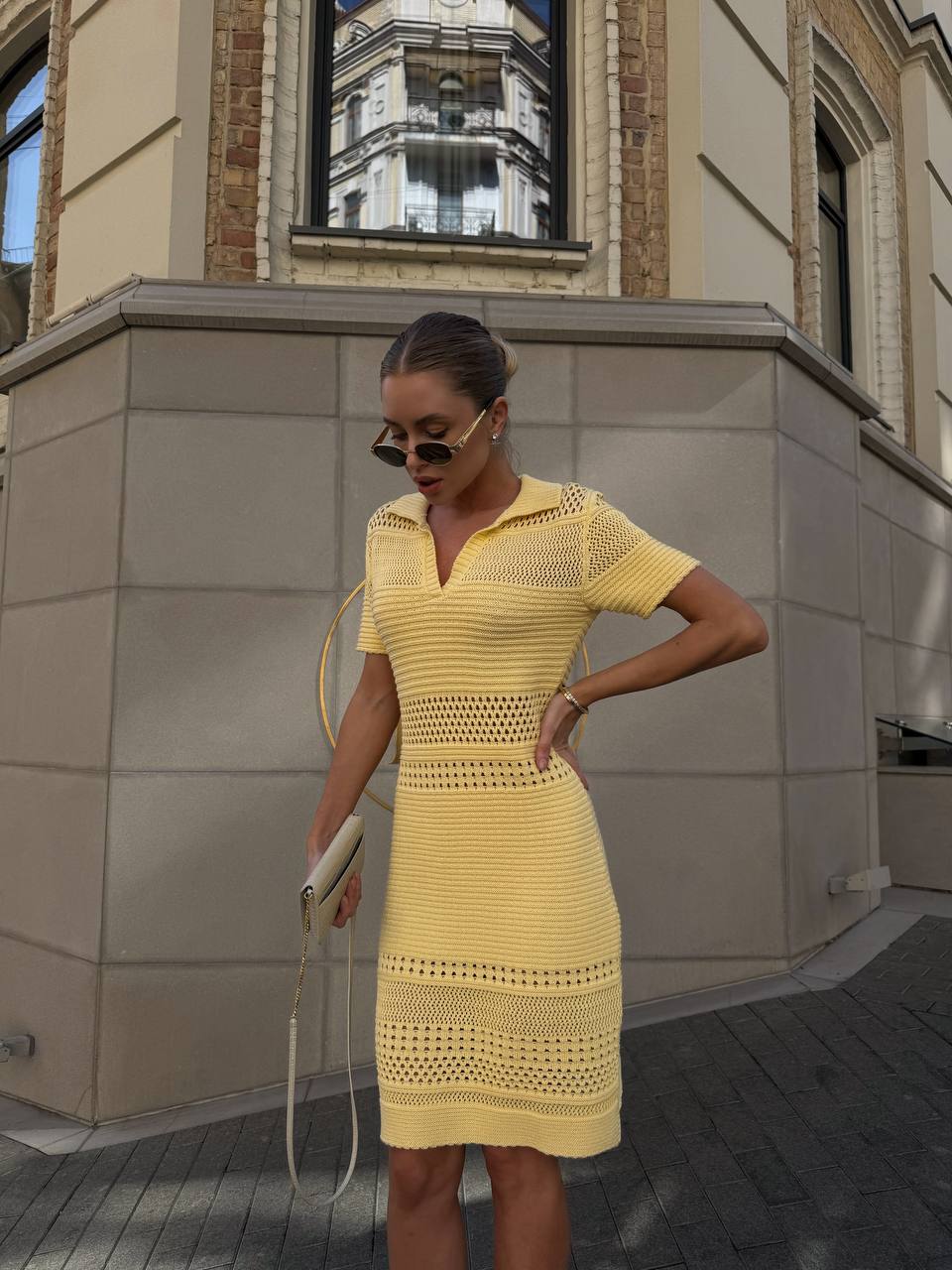 Woman wearing a yellow dress standing in front of a building.