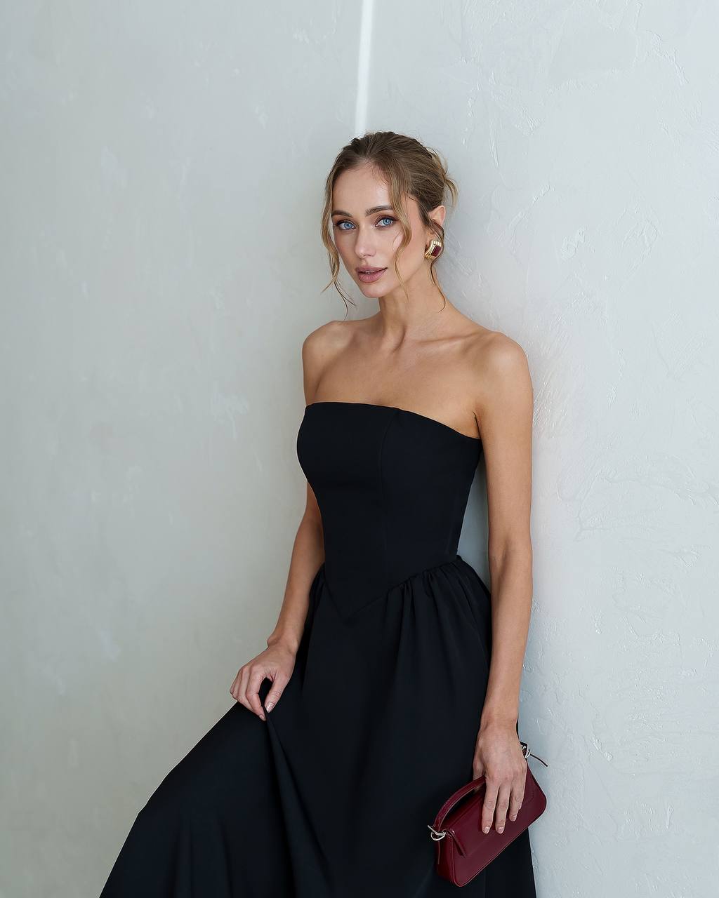 Woman wearing a black strapless dress against a plain background