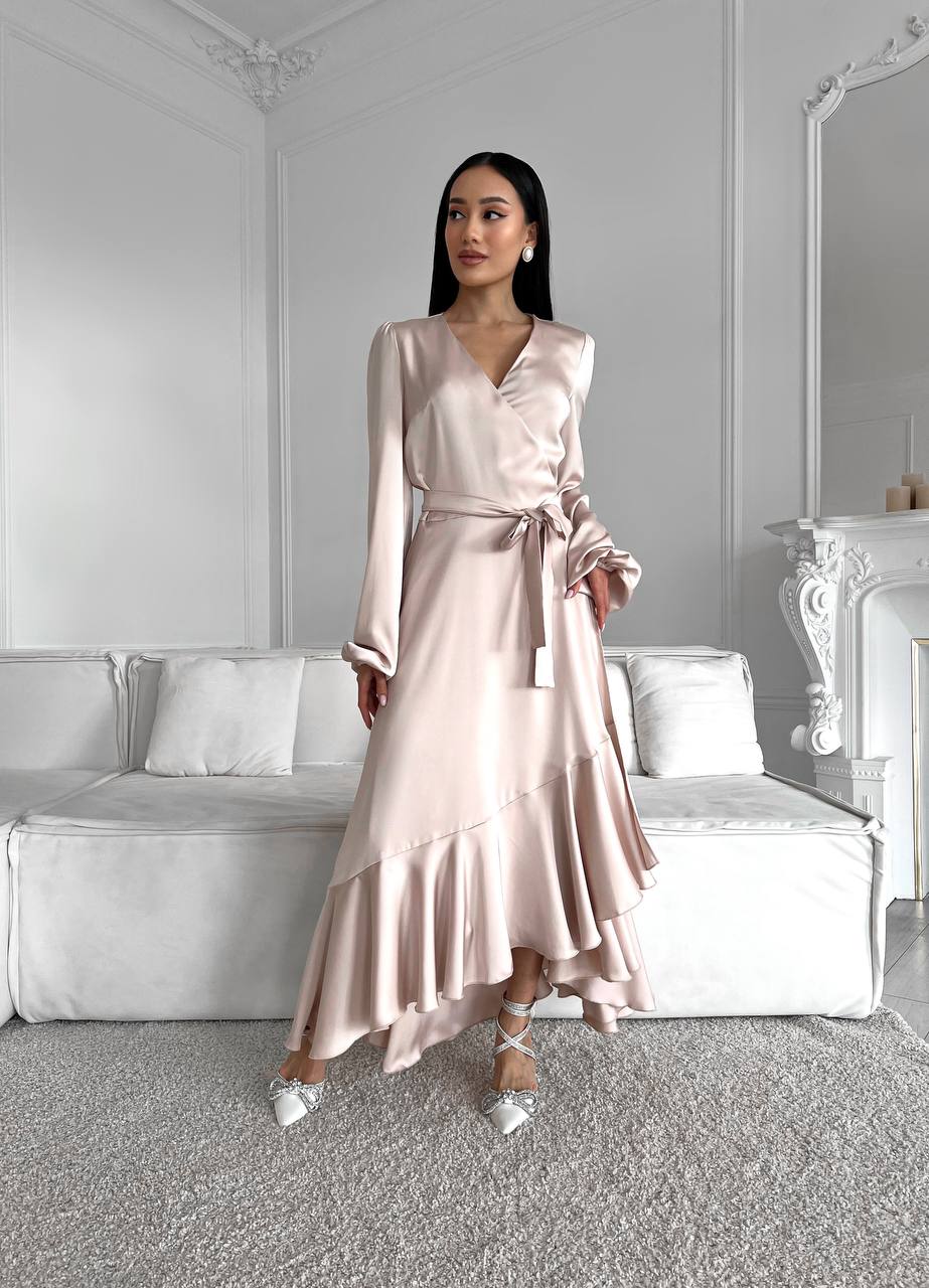 Woman wearing a pink satin dress in a stylish room with white walls and furniture.