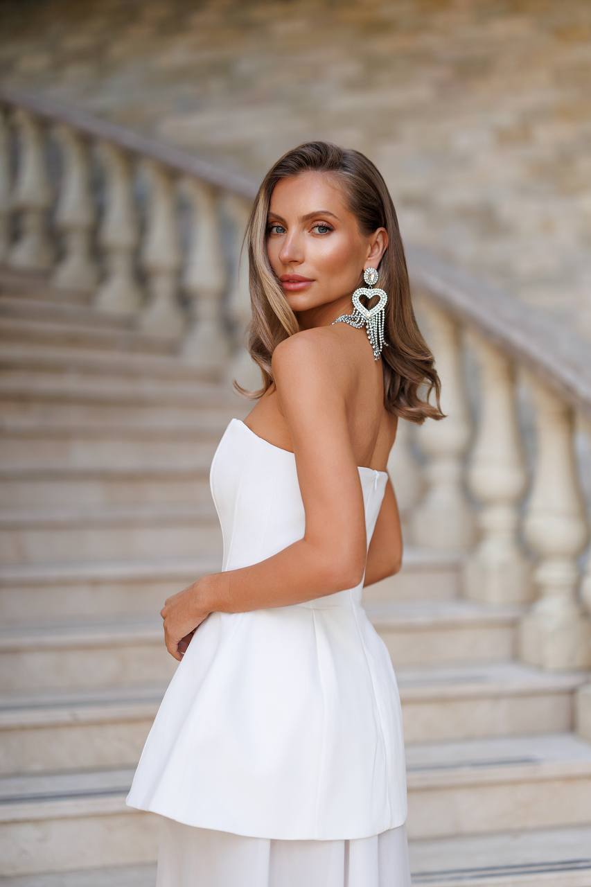 Woman in a white dress standing on stone steps with a blurred background