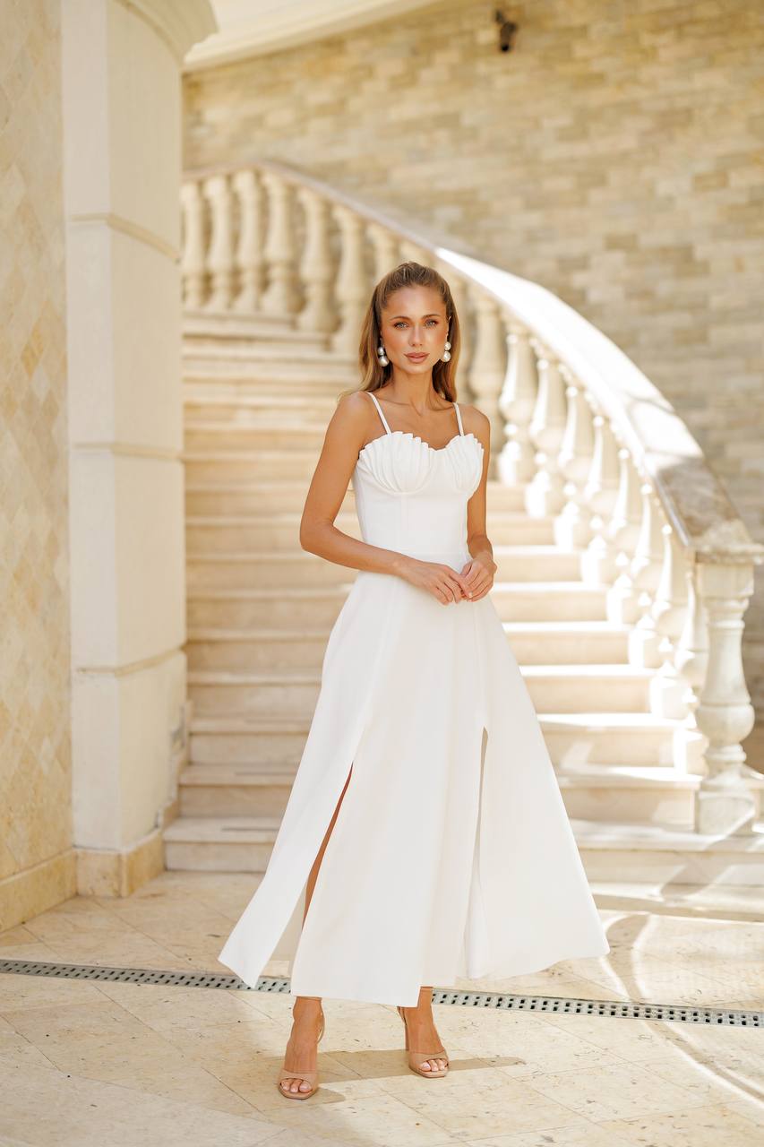 Woman in a white wedding dress standing in front of a classical building with columns.