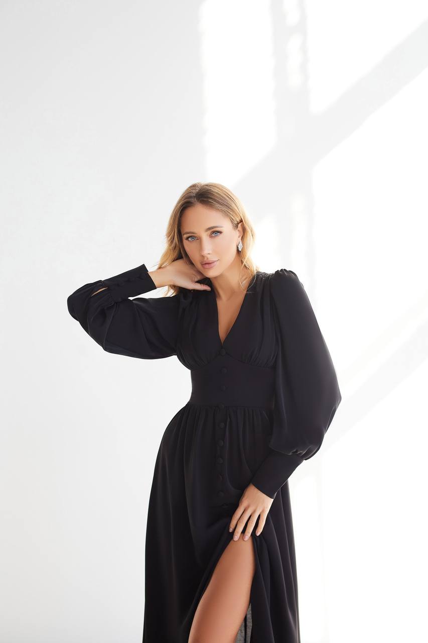 Woman wearing a black dress with a slit on a white background