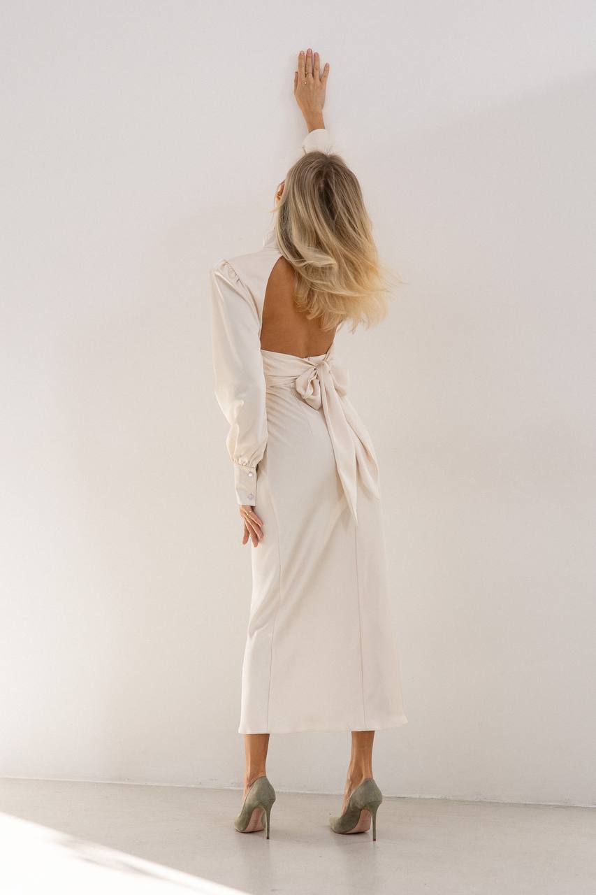 Woman in a white dress standing against a white wall