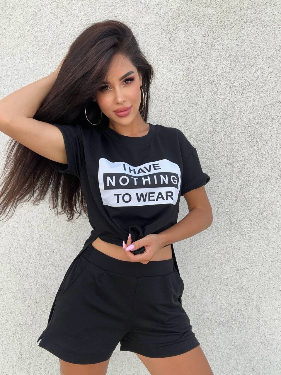 Woman wearing a black t-shirt with 'I have nothing to wear' text against a light gray background