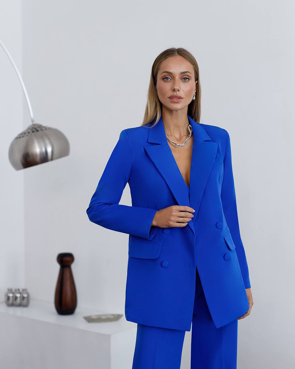 Woman wearing a blue suit in a minimalistic room.