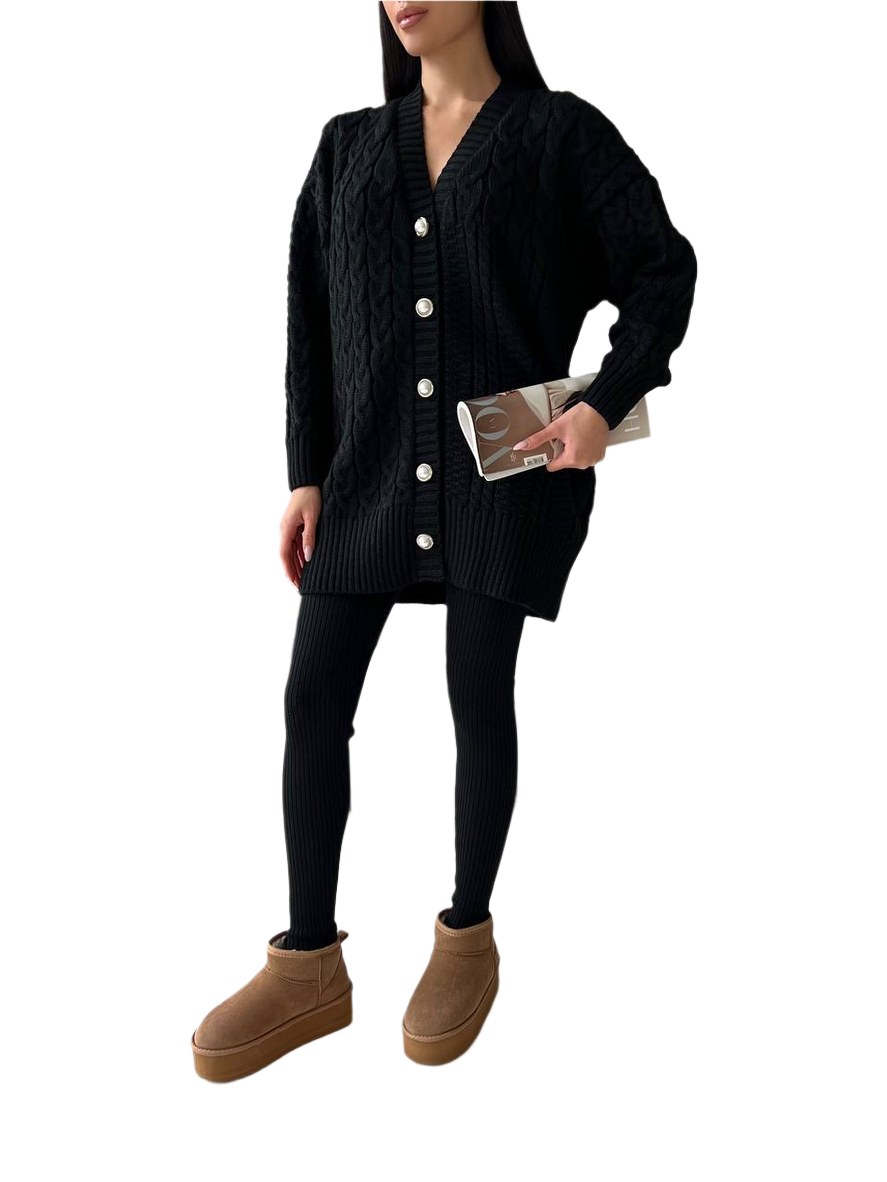 Person wearing a black cardigan, black leggings, and brown boots on a white background