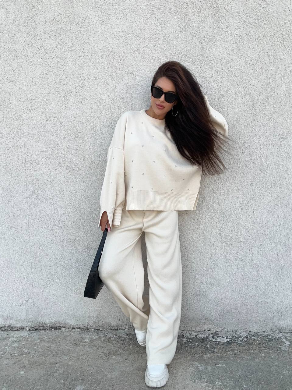 Person wearing a white outfit against a gray wall