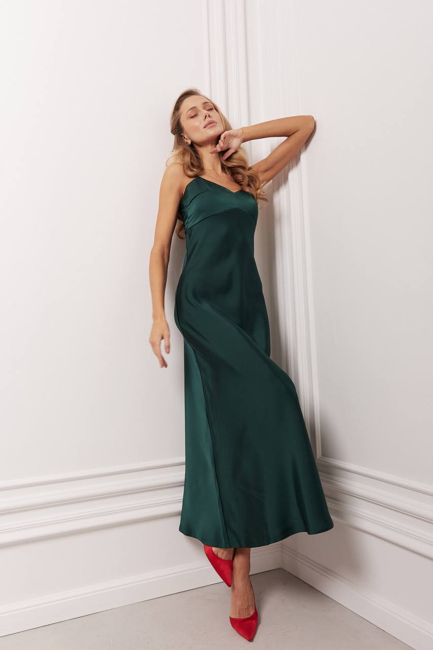 Woman in a green dress standing against a white wall