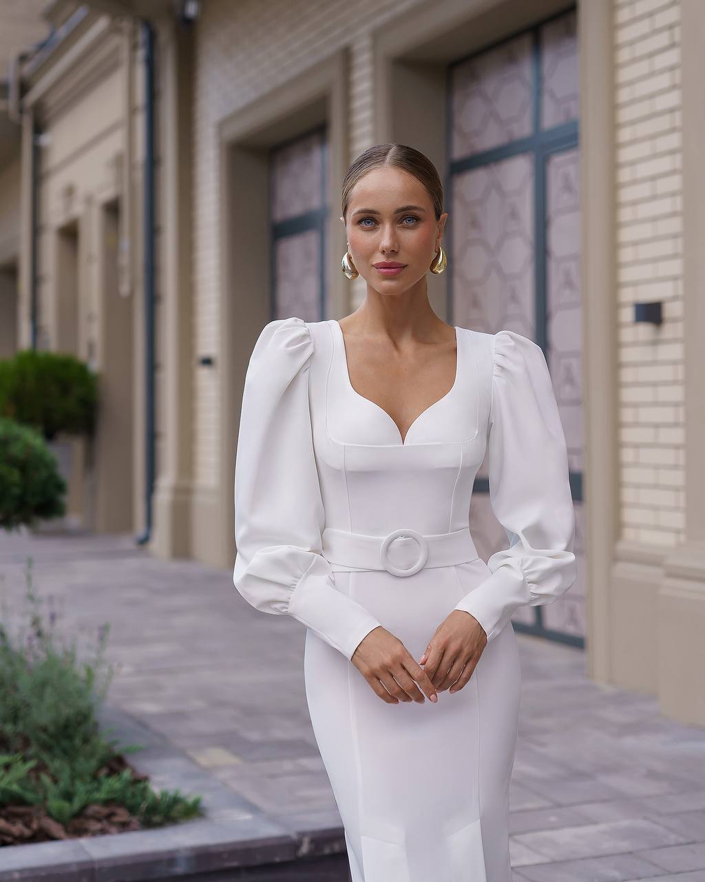 Woman in a white dress standing outdoors with a blurred background