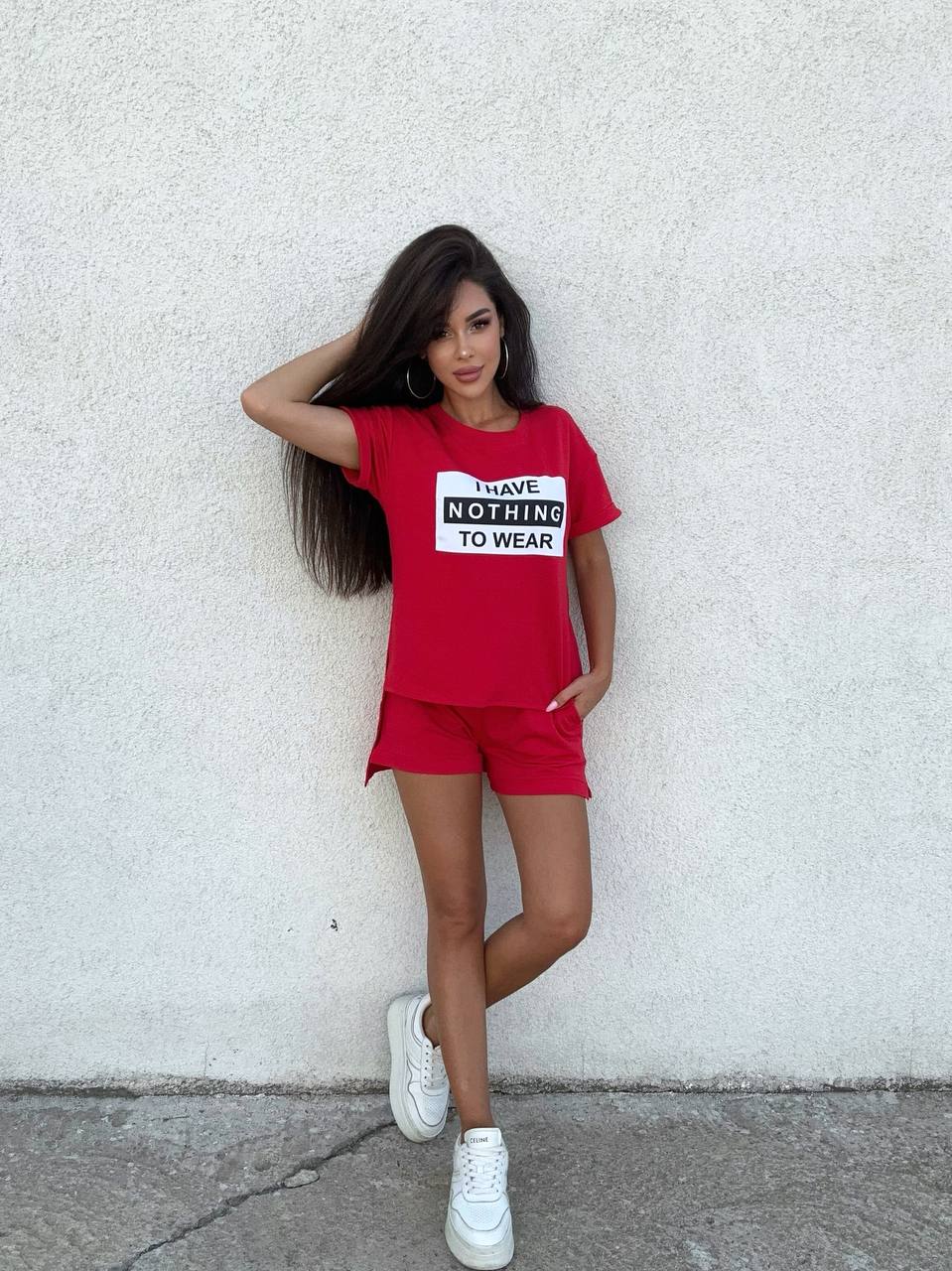 Woman wearing a red outfit with a graphic t-shirt against a white wall