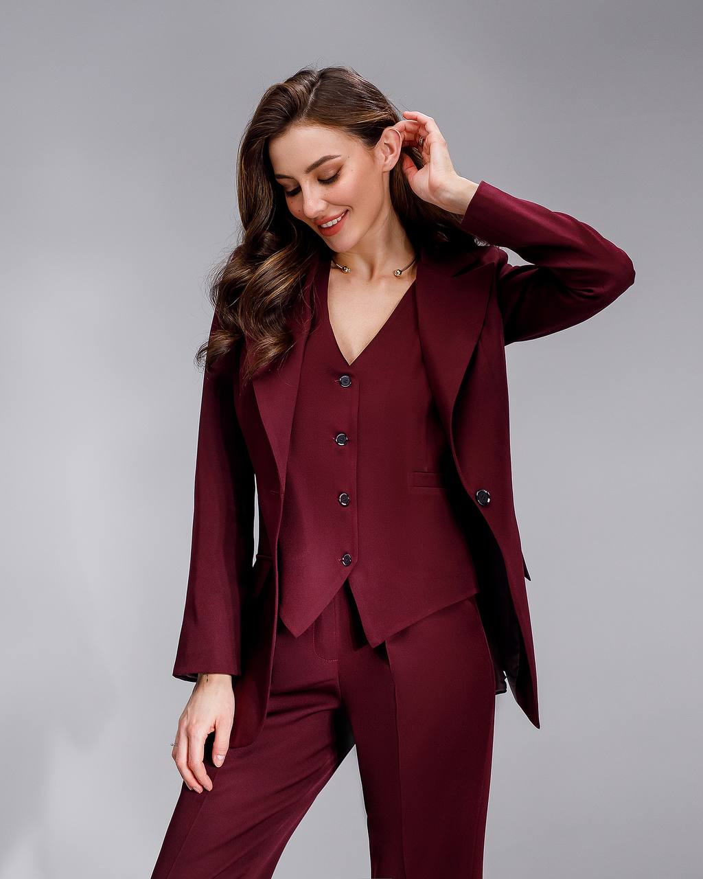 Woman wearing a burgundy suit against a gray background