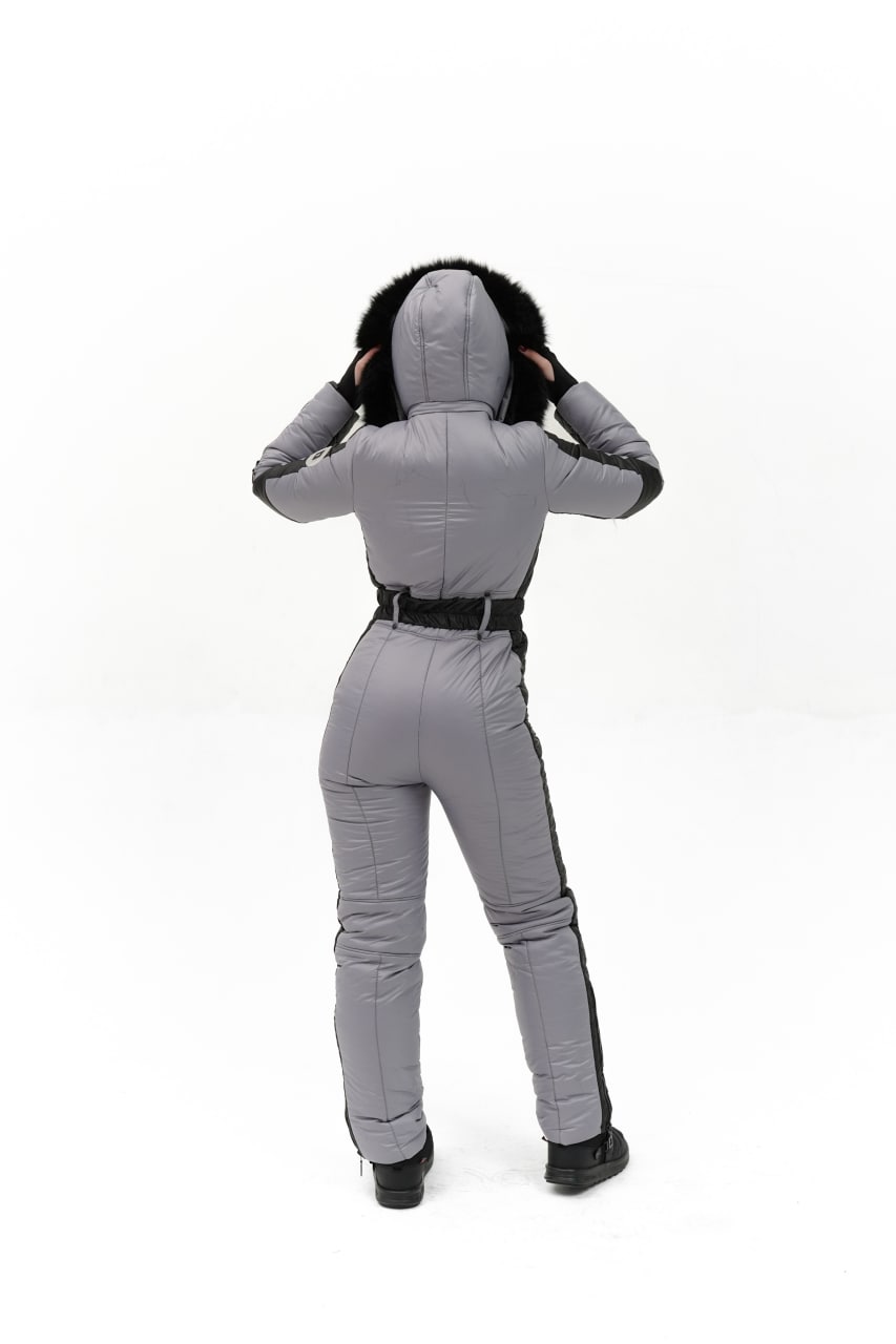 Person wearing a gray jumpsuit with a hood on a white background