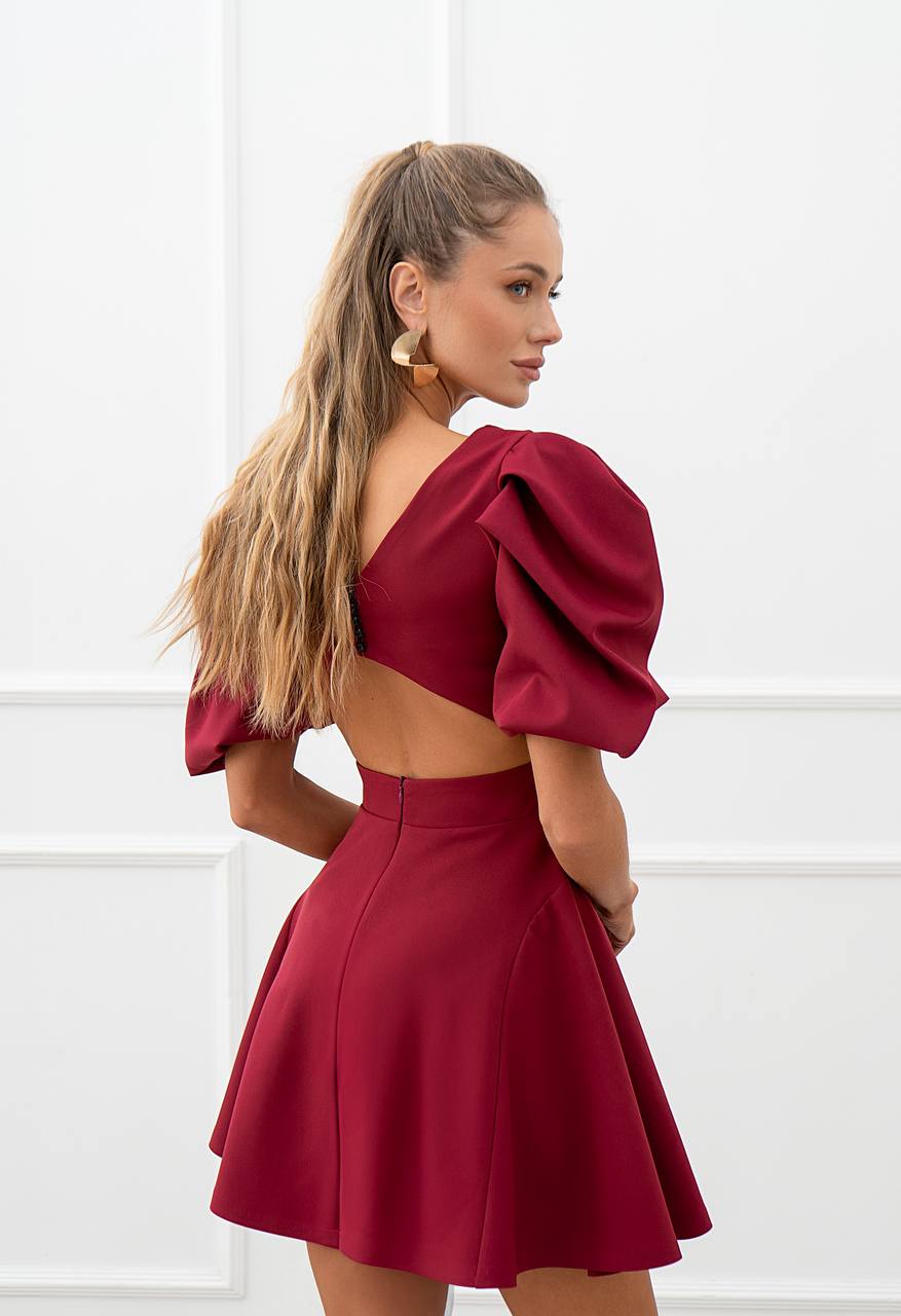 Woman wearing a burgundy two-piece outfit with puffed sleeves against a white background