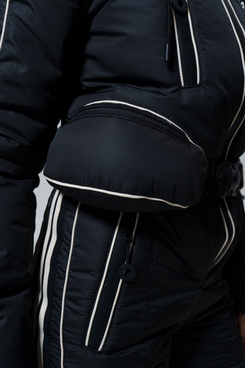 Close-up of a person wearing a black jacket with white piping on a plain background