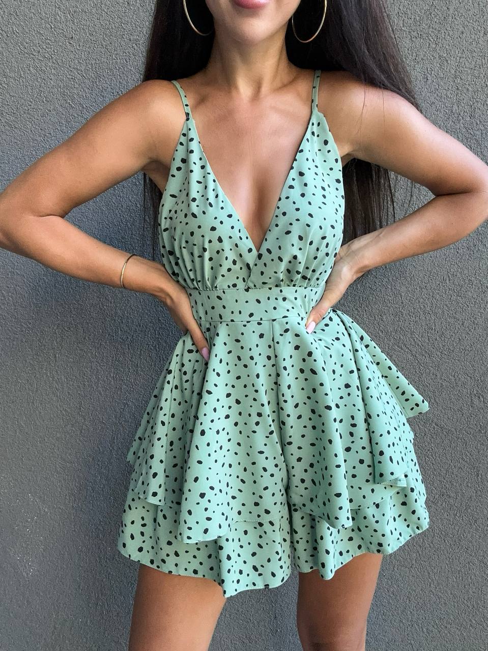 Woman wearing a green polka dot dress against a gray background