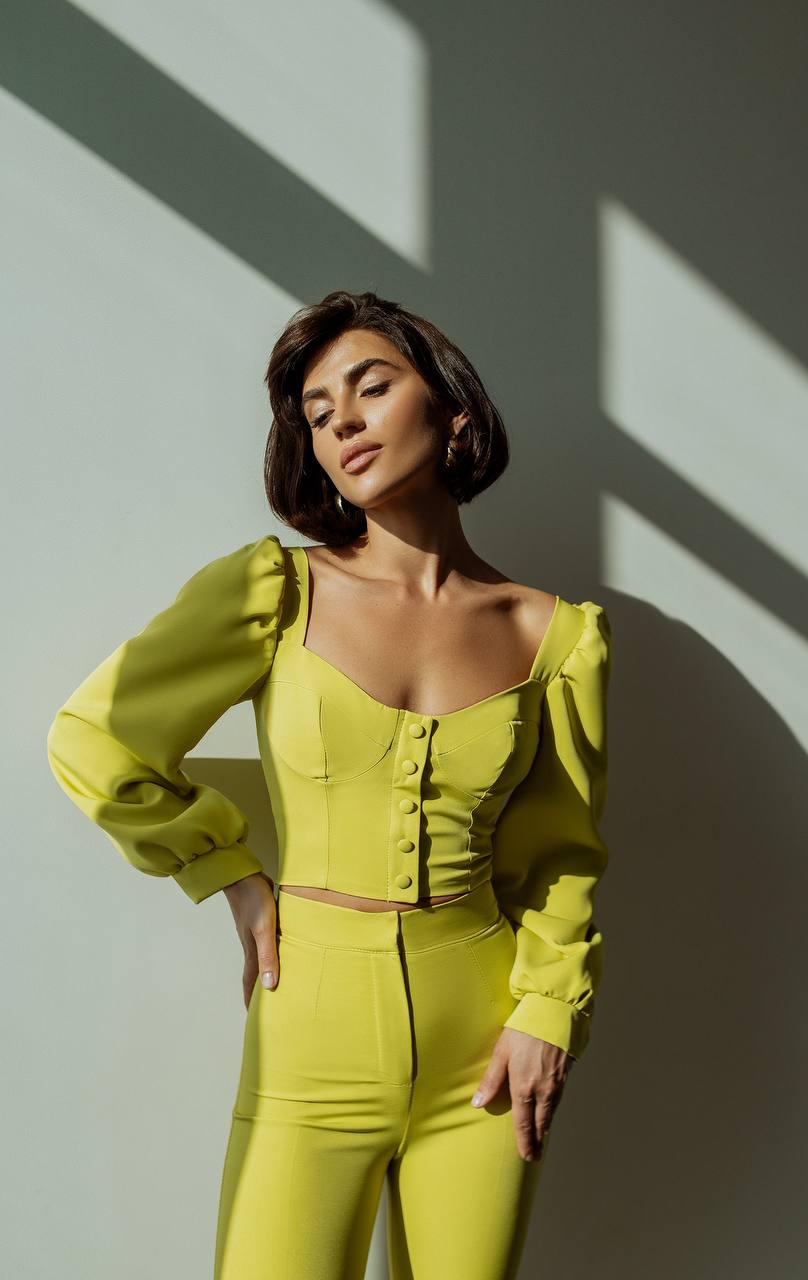 Woman wearing a bright yellow outfit against a light background