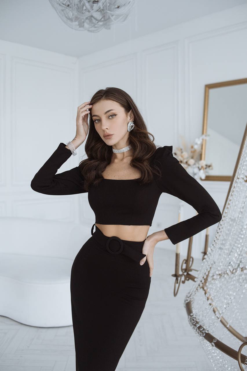 Woman in a black outfit posing in a stylish interior setting