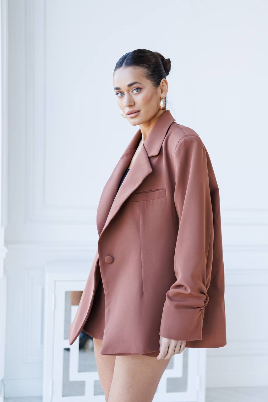 Woman wearing a pink coat and skirt set against a white background