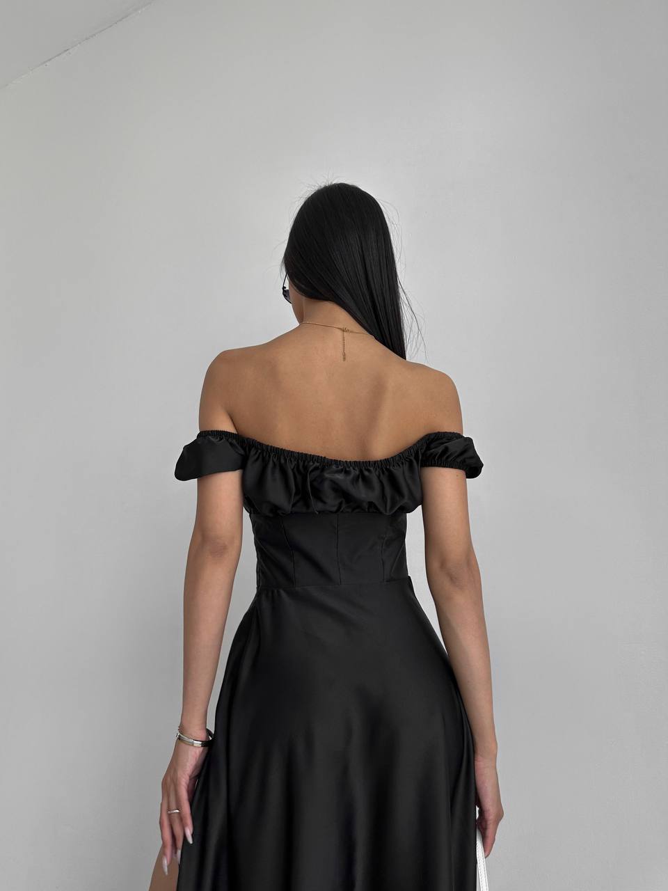 Woman wearing a black off-shoulder dress against a plain background