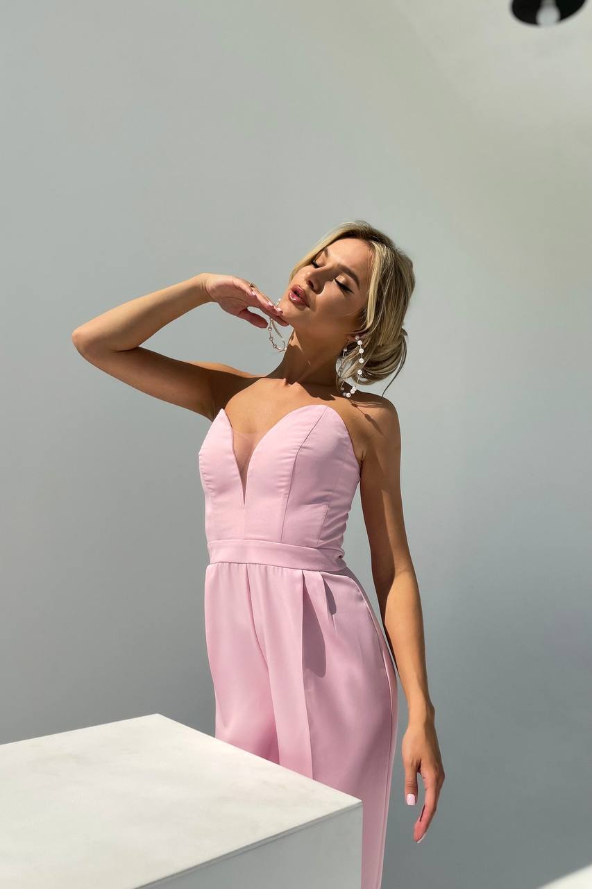 Woman wearing a pink strapless dress against a plain background