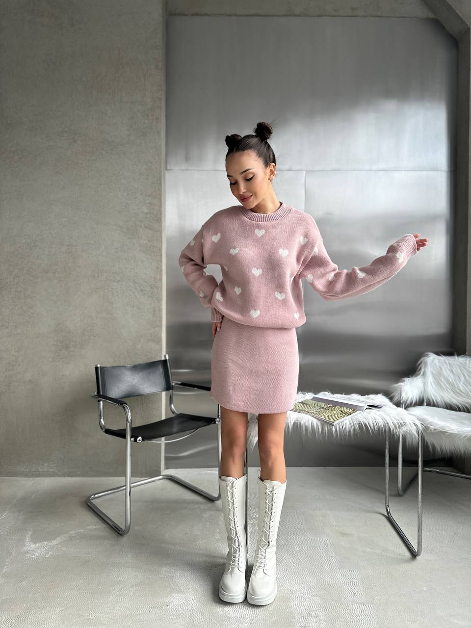 Woman in a pink outfit with heart patterns standing in a modern room.