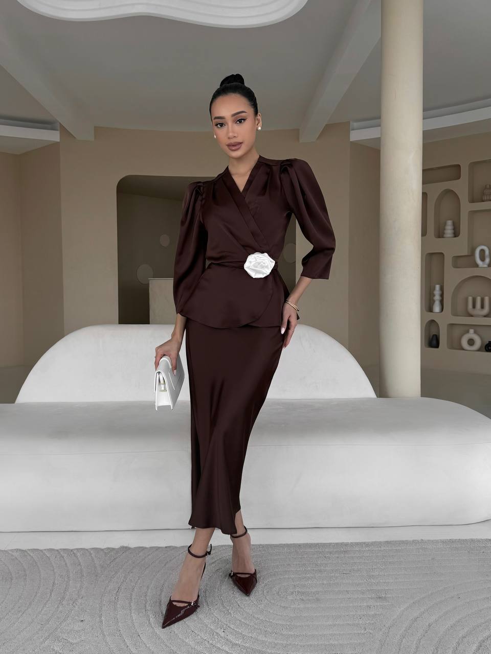 Woman in a brown outfit standing in a modern interior setting