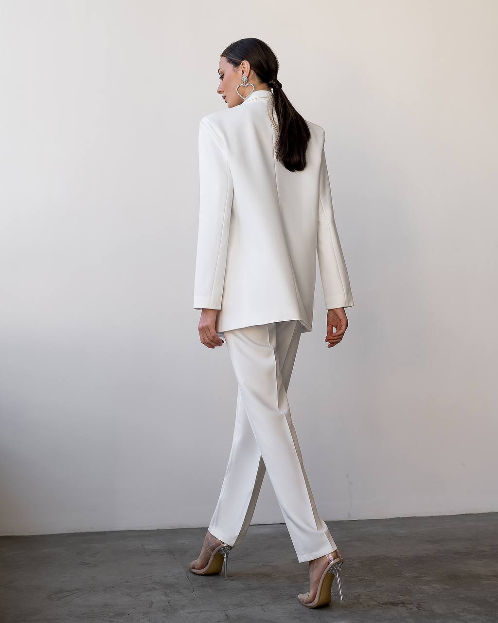 Person wearing a white suit standing against a plain background