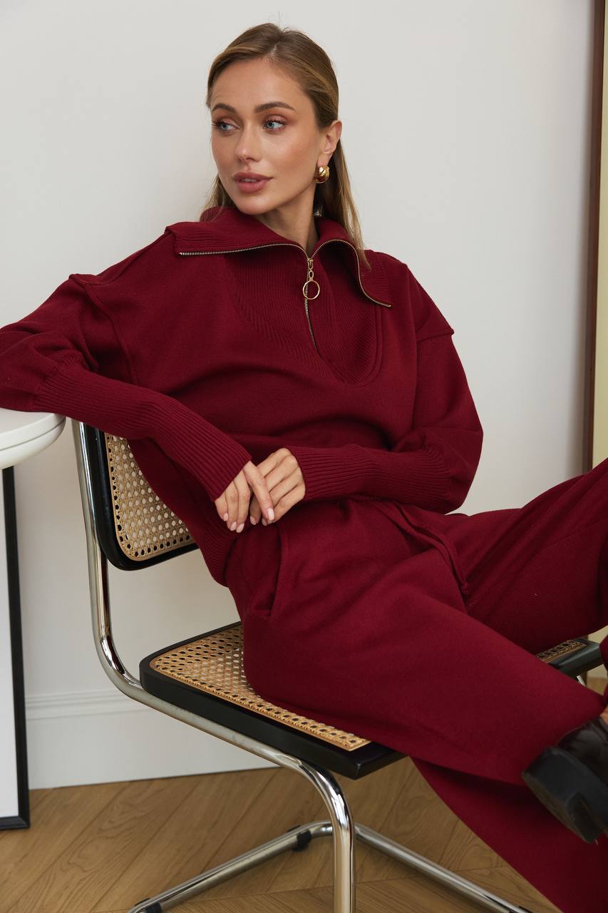 Woman wearing a burgundy outfit sitting on a chair.