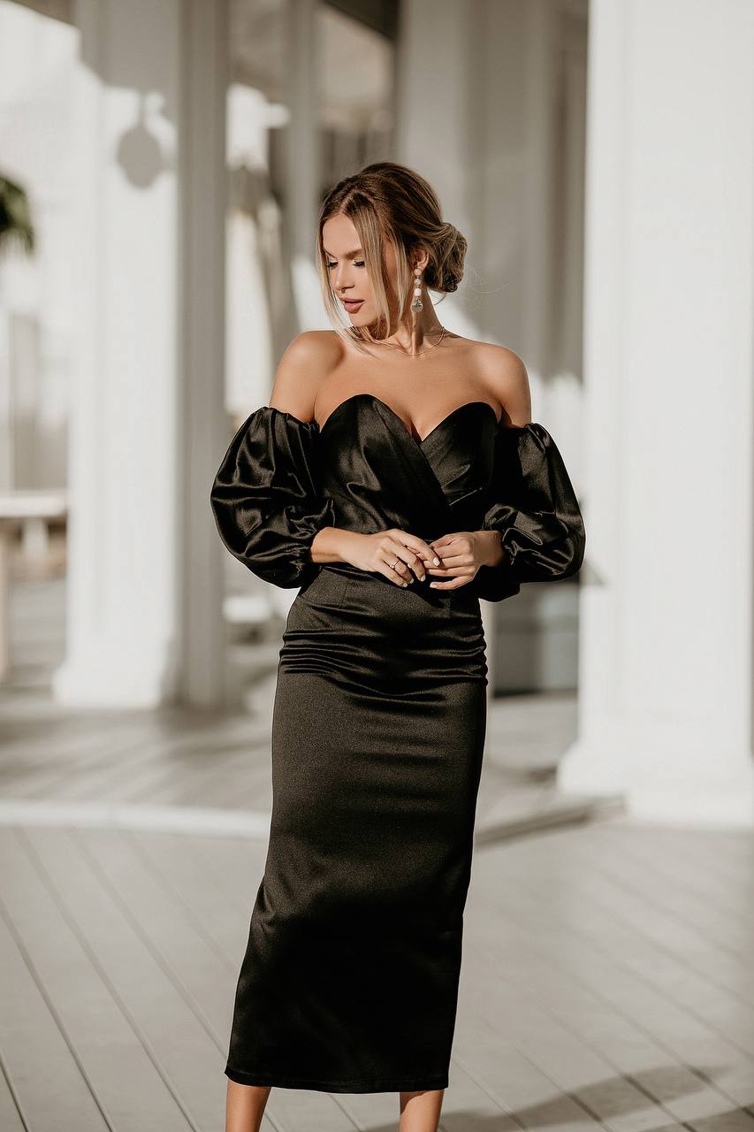 Woman wearing a black dress with puffed sleeves in an outdoor setting