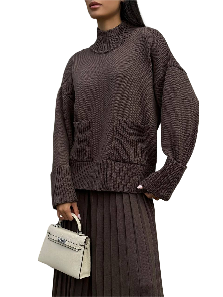 Person wearing a brown sweater holding a white handbag on a white background